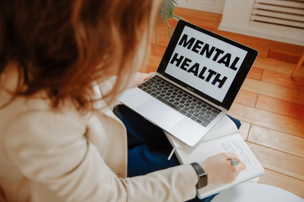 Mulher participa de uma sessão de terapia online diante de um laptop e faz anotações.