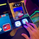 Mão interage com botões de uma interface colorida de máquina caça-níqueis digital.