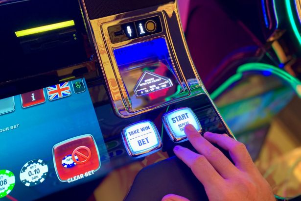 Mão interage com botões de uma interface colorida de máquina caça-níqueis digital.