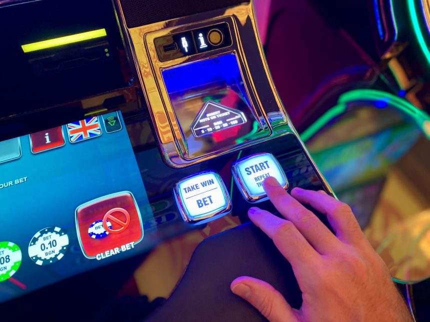 Mão interage com botões de uma interface colorida de máquina caça-níqueis digital.